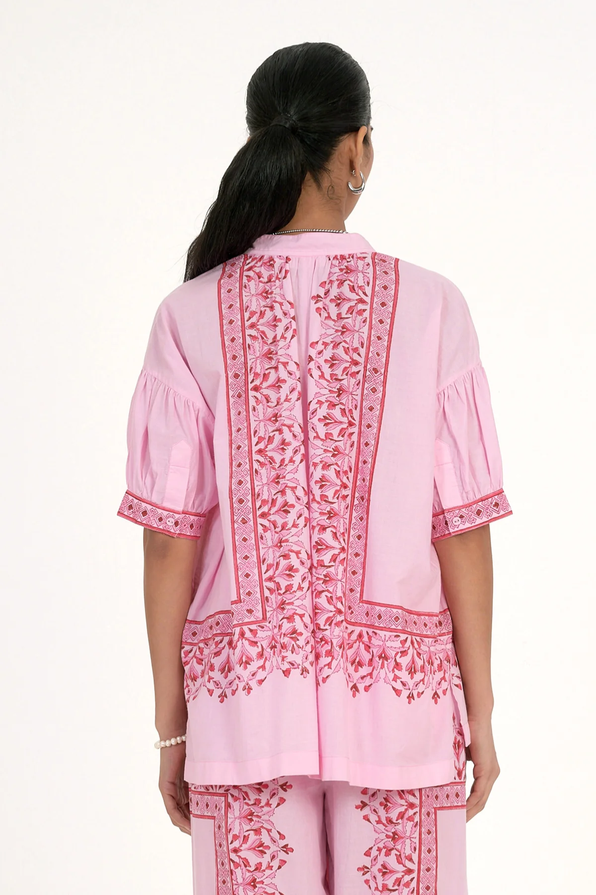 Woman wearing a pink embroidered traditional outfit on a white background