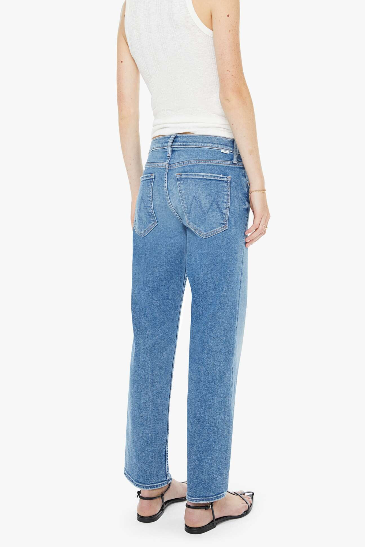 Person wearing blue jeans and a white top on a white background