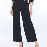 woman in wide leg black pants and gold buttons on white background 