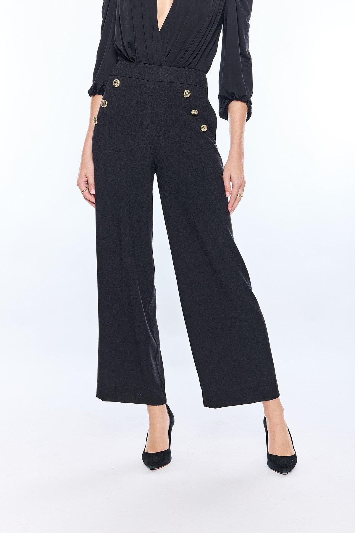 woman in wide leg black pants and gold buttons on white background 