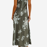 A woman modeling a sleeveless olive green satin maxi dress with a white floral print, shown from the back against a light gray background.