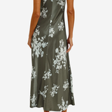 A woman modeling a sleeveless olive green satin maxi dress with a white floral print, shown from the back against a light gray background.