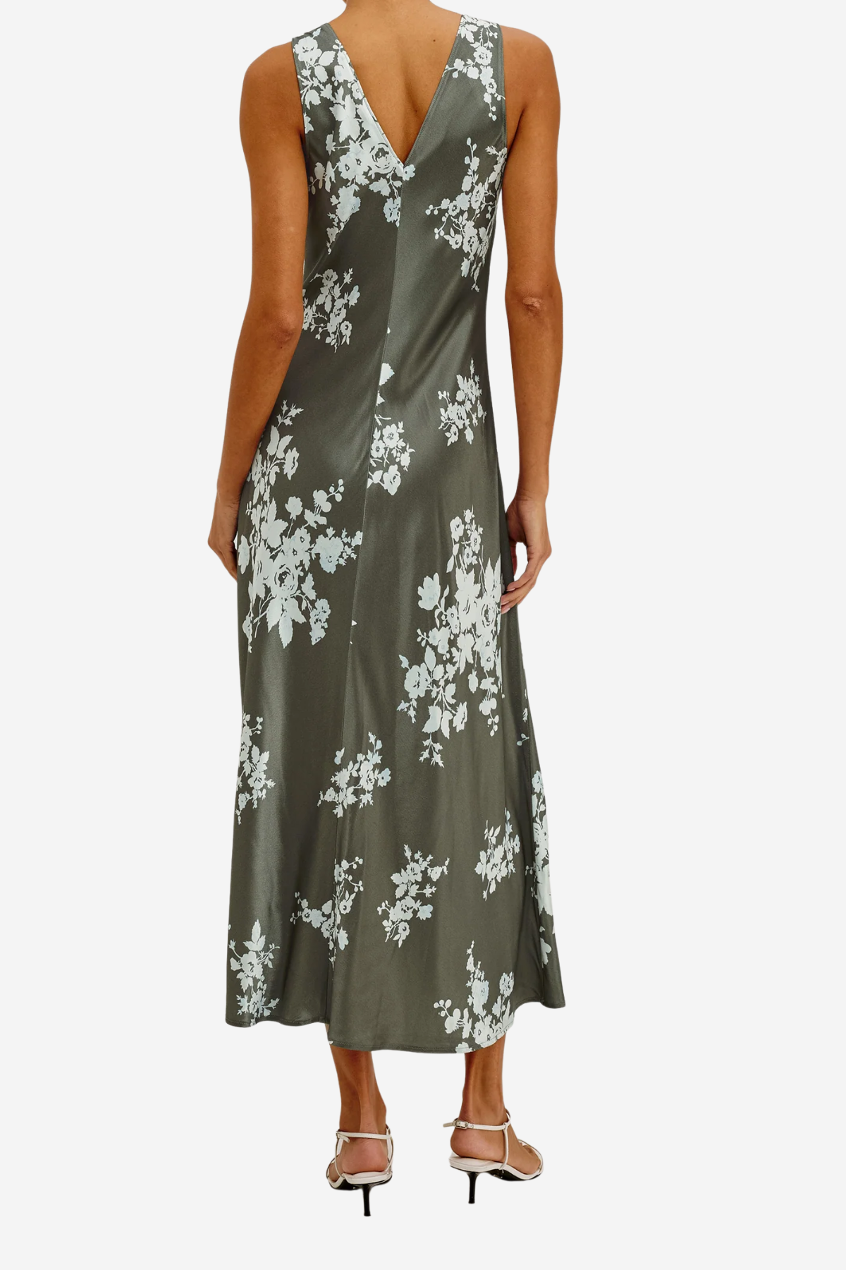 A woman modeling a sleeveless olive green satin maxi dress with a white floral print, shown from the back against a light gray background.