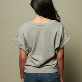 Person wearing a gray oversized t-shirt and blue jeans against a beige background