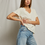Woman wearing a white top and light blue jeans against a plain background