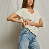 Woman wearing a white top and light blue jeans against a plain background
