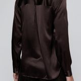 A dark brown long-sleeve satin shirt shown from the back on a model, paired with dark trousers, against a light gray studio background.