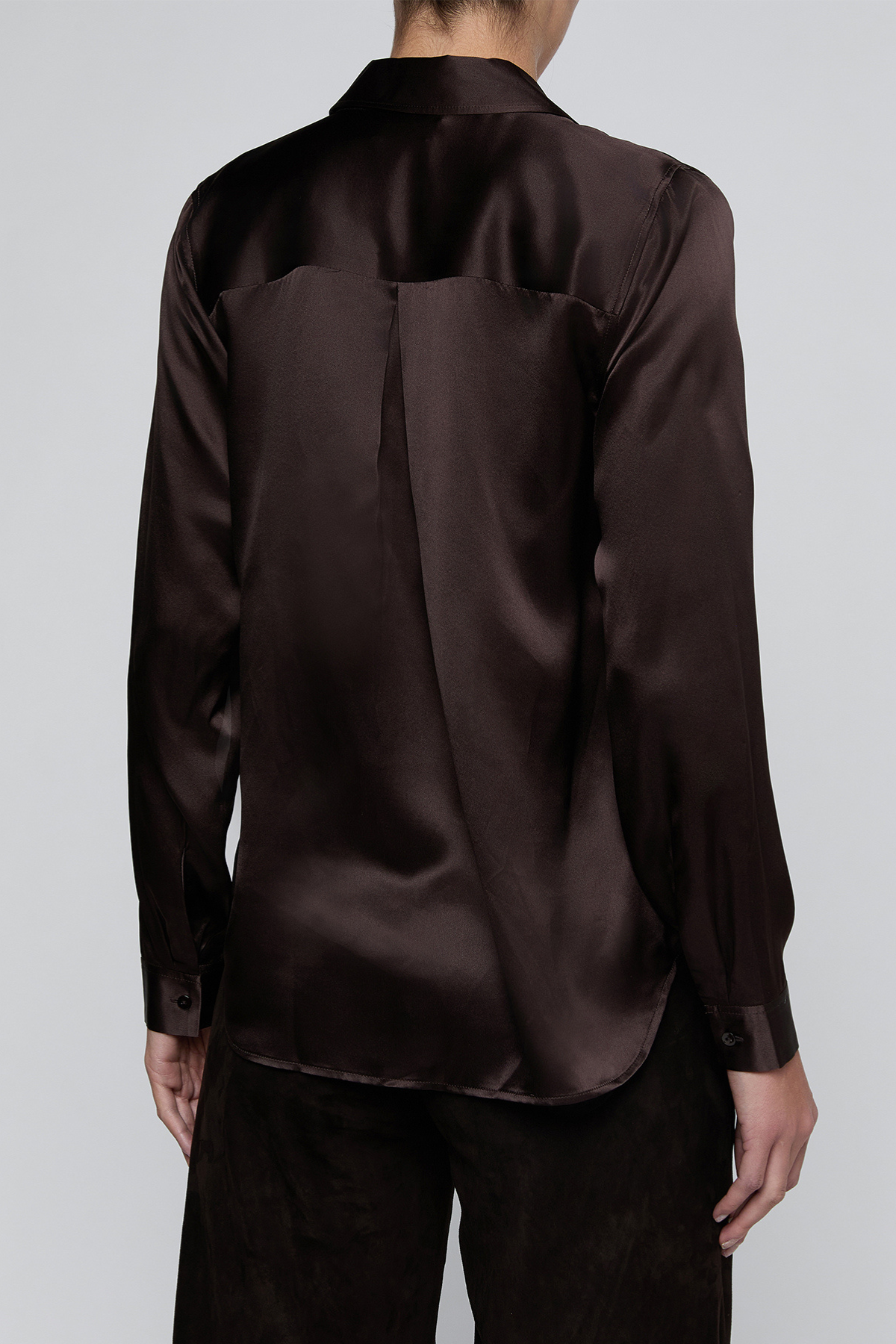 A dark brown long-sleeve satin shirt shown from the back on a model, paired with dark trousers, against a light gray studio background.