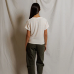 Person wearing a white striped shirt and green pants standing against a plain white background