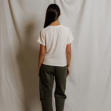 Person wearing a white striped shirt and green pants standing against a plain white background