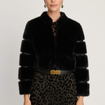 Woman wearing a black fur coat with a gold belt and leopard print skirt on a white background