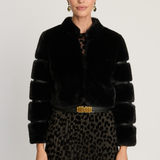 Woman wearing a black fur coat with a gold belt and leopard print skirt on a white background