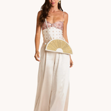 Woman wearing a white dress with floral details, holding a fan, on a white background