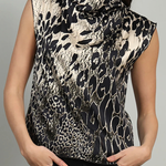 A woman wearing a sleeveless high-neck top with a black and beige animal print pattern, paired with black pants, against a plain gray background.