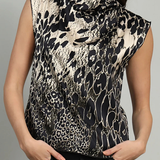 A woman wearing a sleeveless high-neck top with a black and beige animal print pattern, paired with black pants, against a plain gray background.