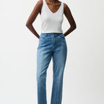 Woman wearing a white tank top and blue jeans on a white background