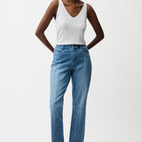 Woman wearing a white tank top and blue jeans on a white background