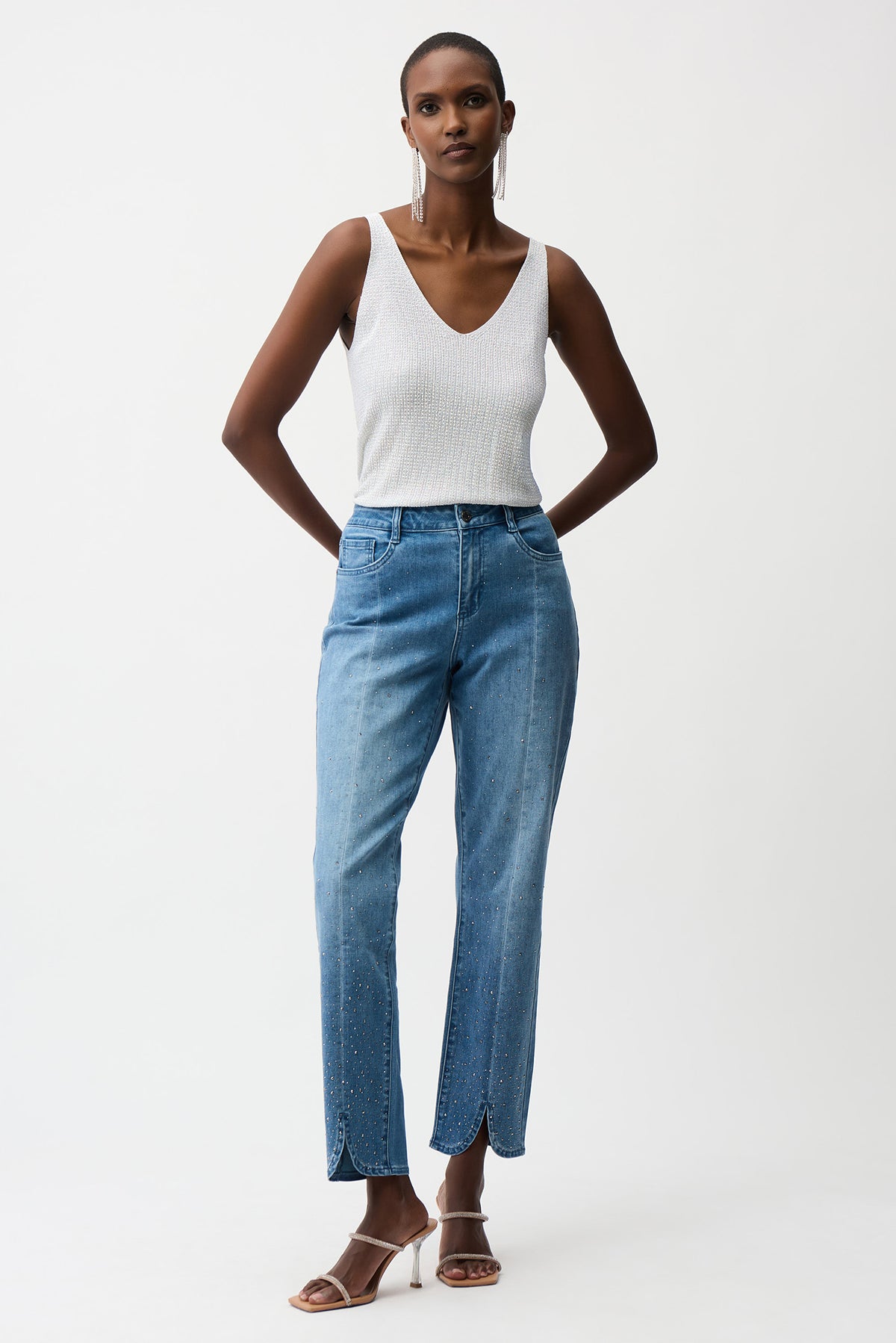 Woman wearing a white tank top and blue jeans on a white background