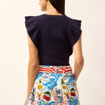 Woman wearing a navy top and colorful patterned skirt on a beige background