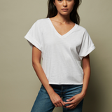 Woman wearing a white t-shirt and blue jeans against a beige background