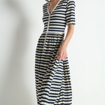 Woman wearing a black and white striped dress against a plain background