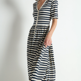 Woman wearing a black and white striped dress against a plain background