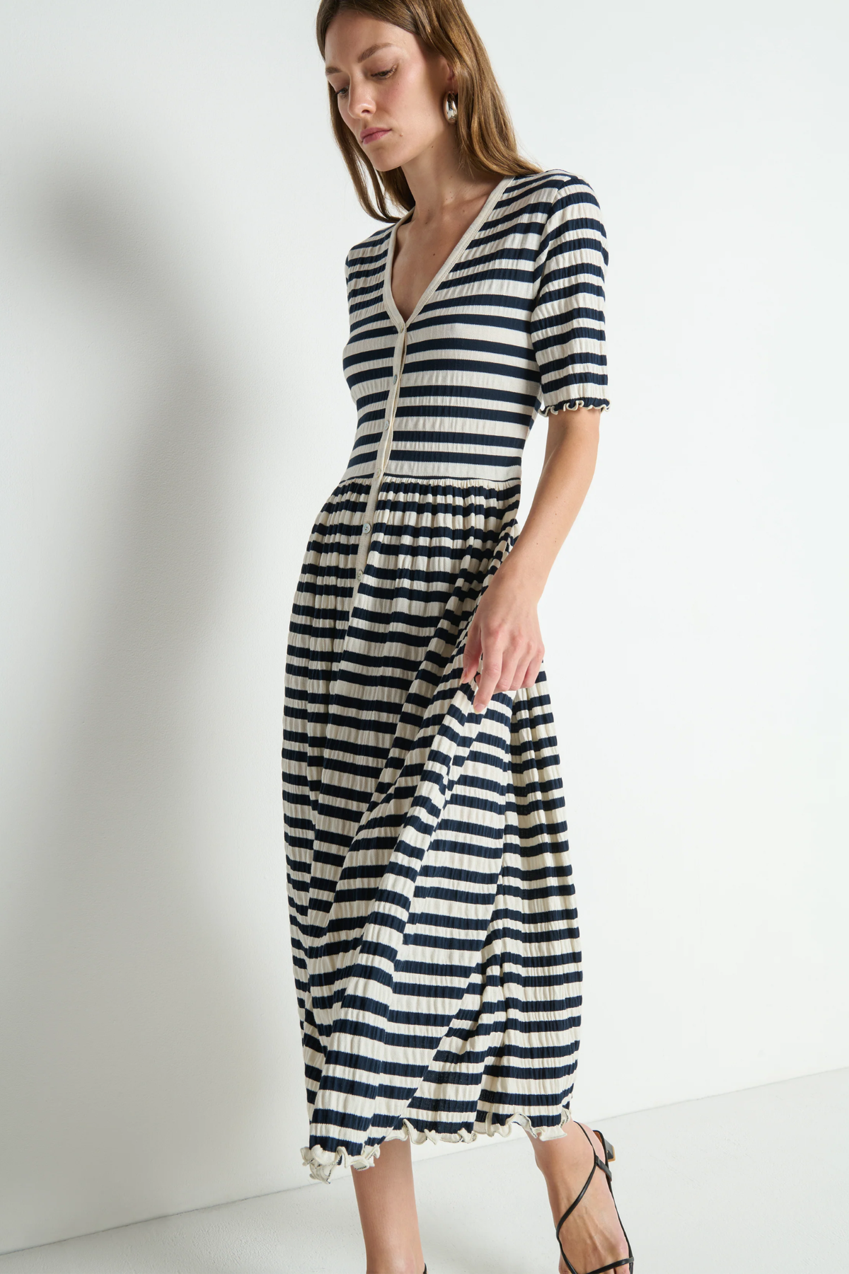 Woman wearing a black and white striped dress against a plain background