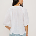 Woman wearing a white blouse and denim shorts on a plain background