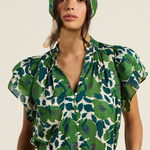 woman in green floral blouse on tan background 