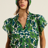 woman in green floral blouse on tan background 