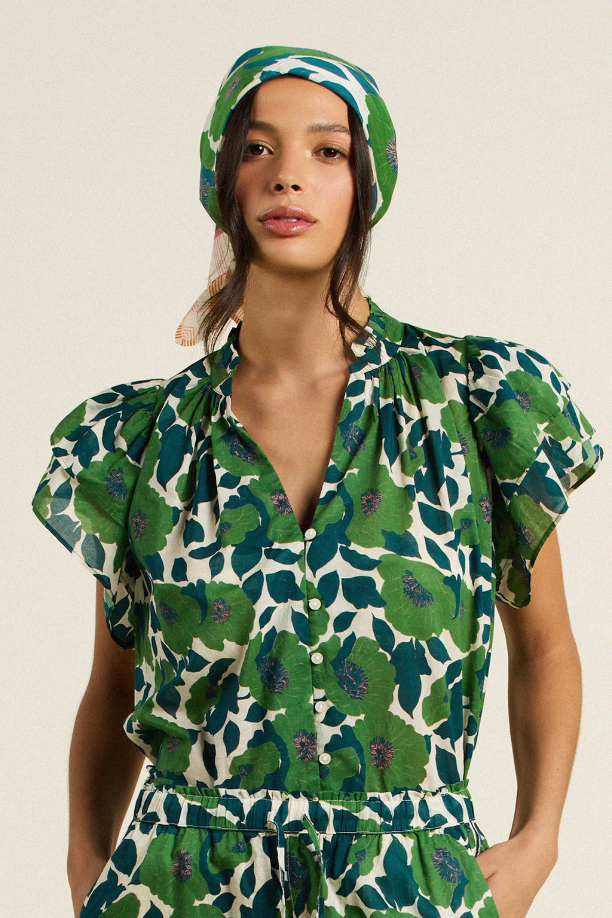 woman in green floral blouse on tan background 