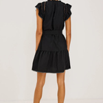 Woman wearing a black dress with ruffled sleeves on a white background