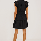 Woman wearing a black dress with ruffled sleeves on a white background