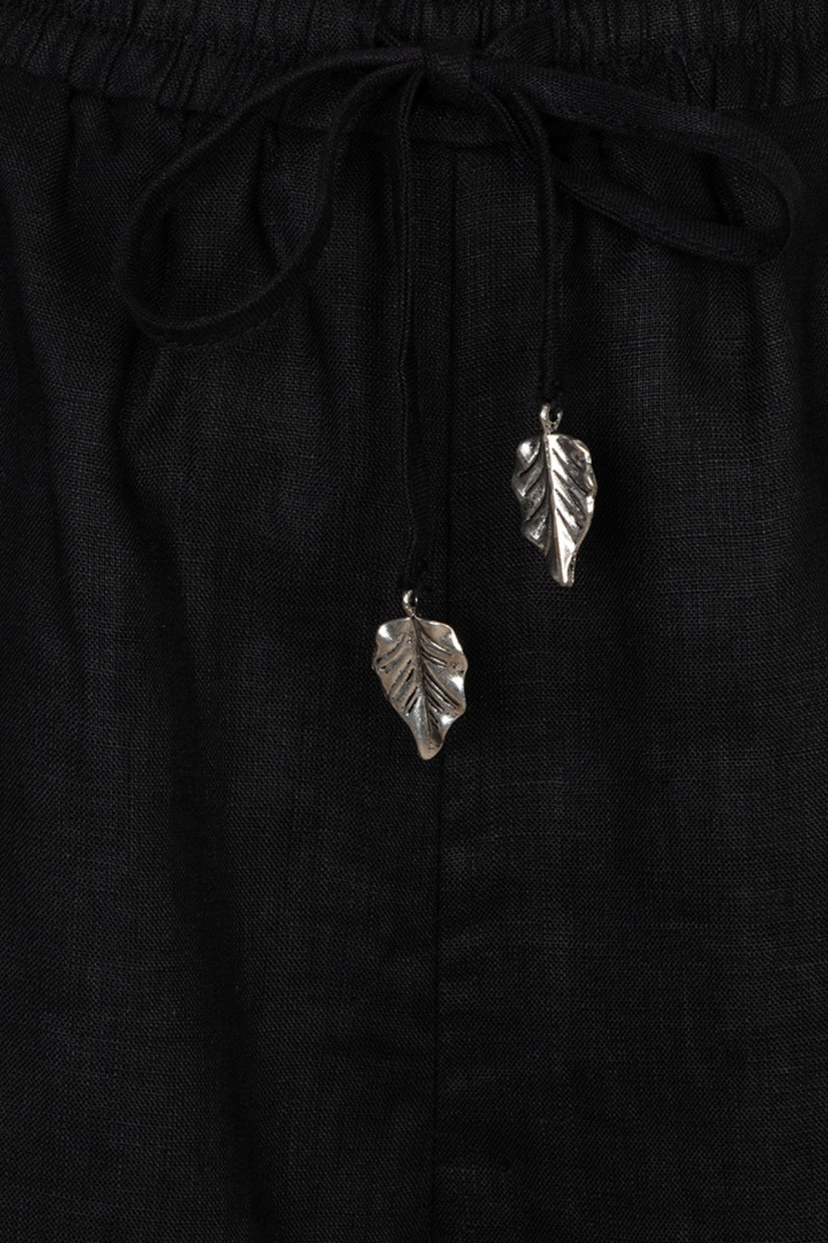 Silver leaf earrings on a black fabric background