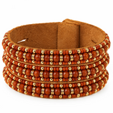 A wide brown suede cuff bracelet decorated with multiple rows of orange-red beads and small gold spacer rings, shown on a plain white background.