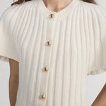 White ribbed knit cardigan with gold buttons worn by a person on a white background