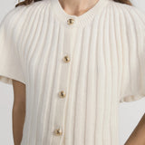 White ribbed knit cardigan with gold buttons worn by a person on a white background
