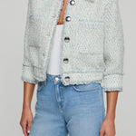 Person wearing a light blue textured jacket and jeans on a gray background