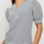 Woman wearing a black and white striped shirt with blue jeans against a plain background