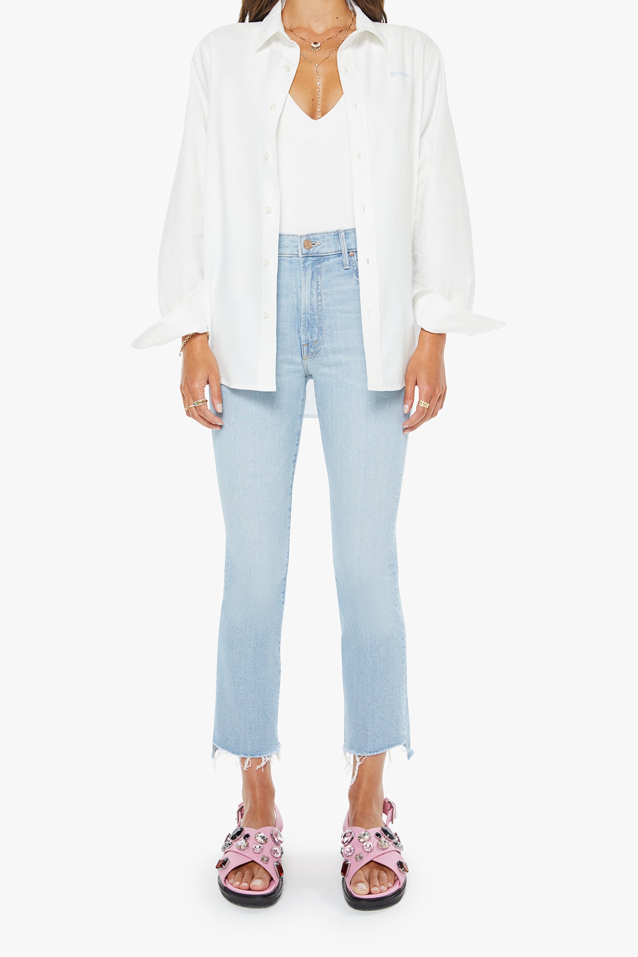 Person wearing a white shirt, light blue jeans, and pink sandals on a white background