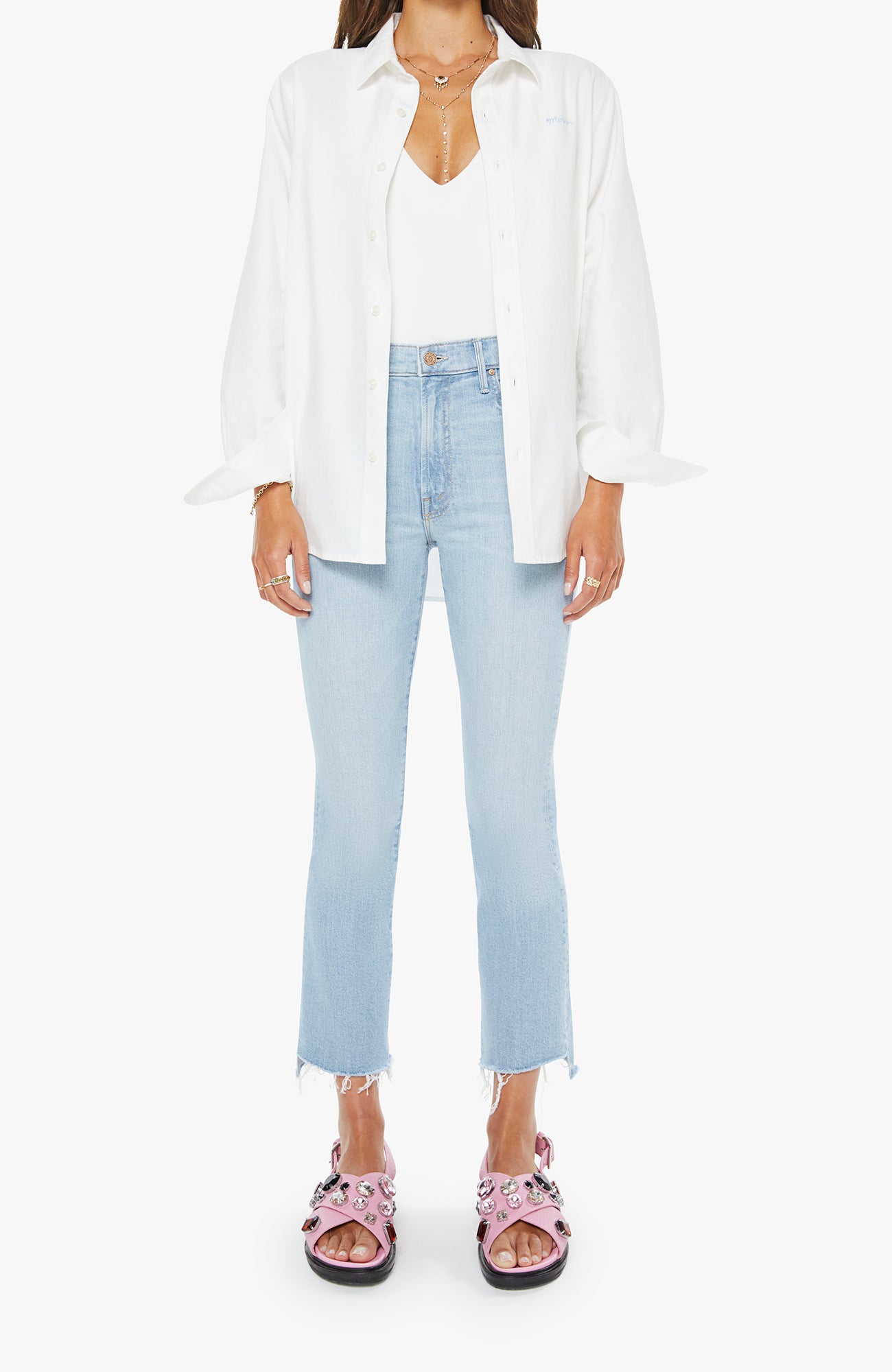 Person wearing a white shirt, light blue jeans, and pink sandals on a white background