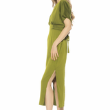 Woman wearing a green dress with a slit on a white background
