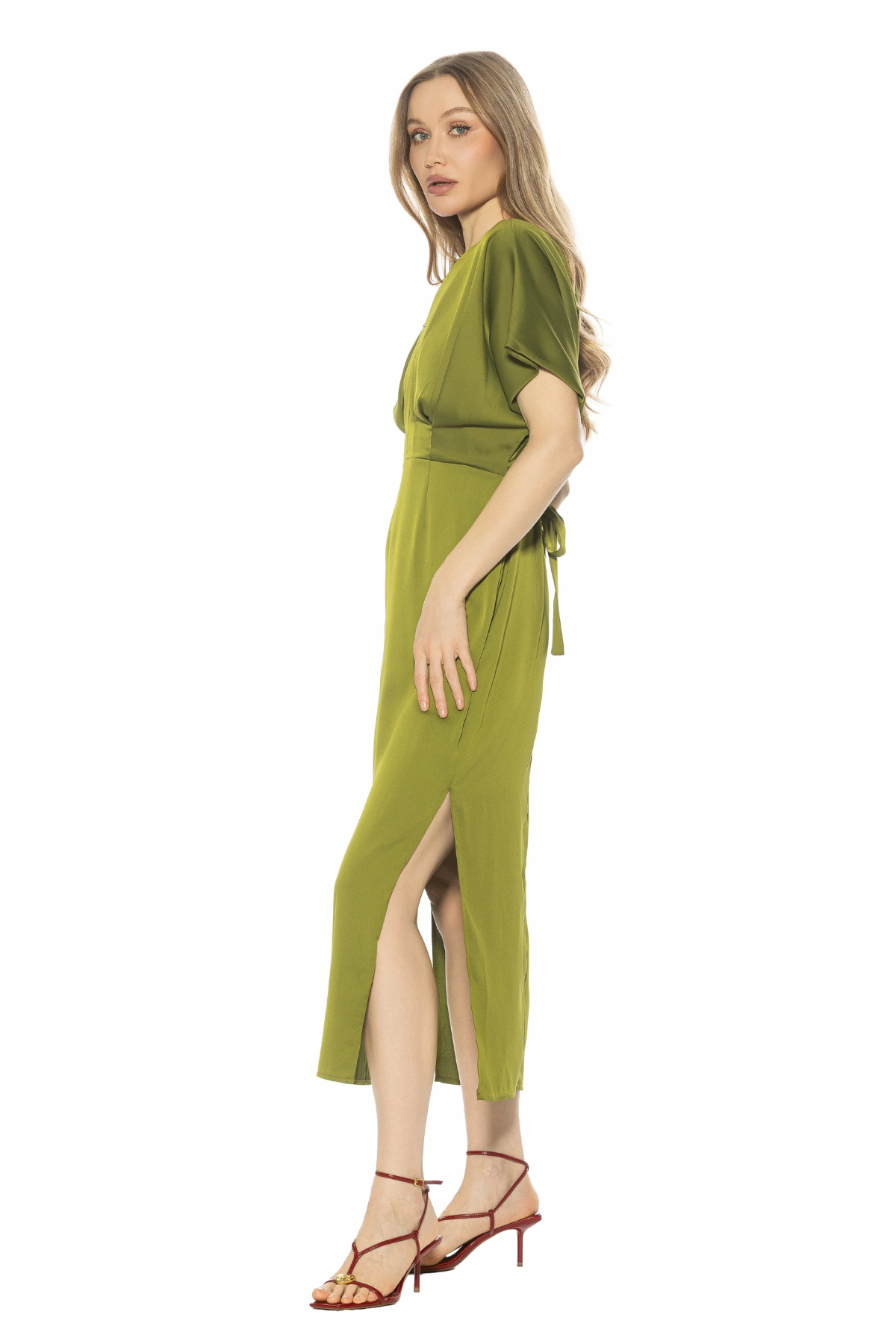 Woman wearing a green dress with a slit on a white background