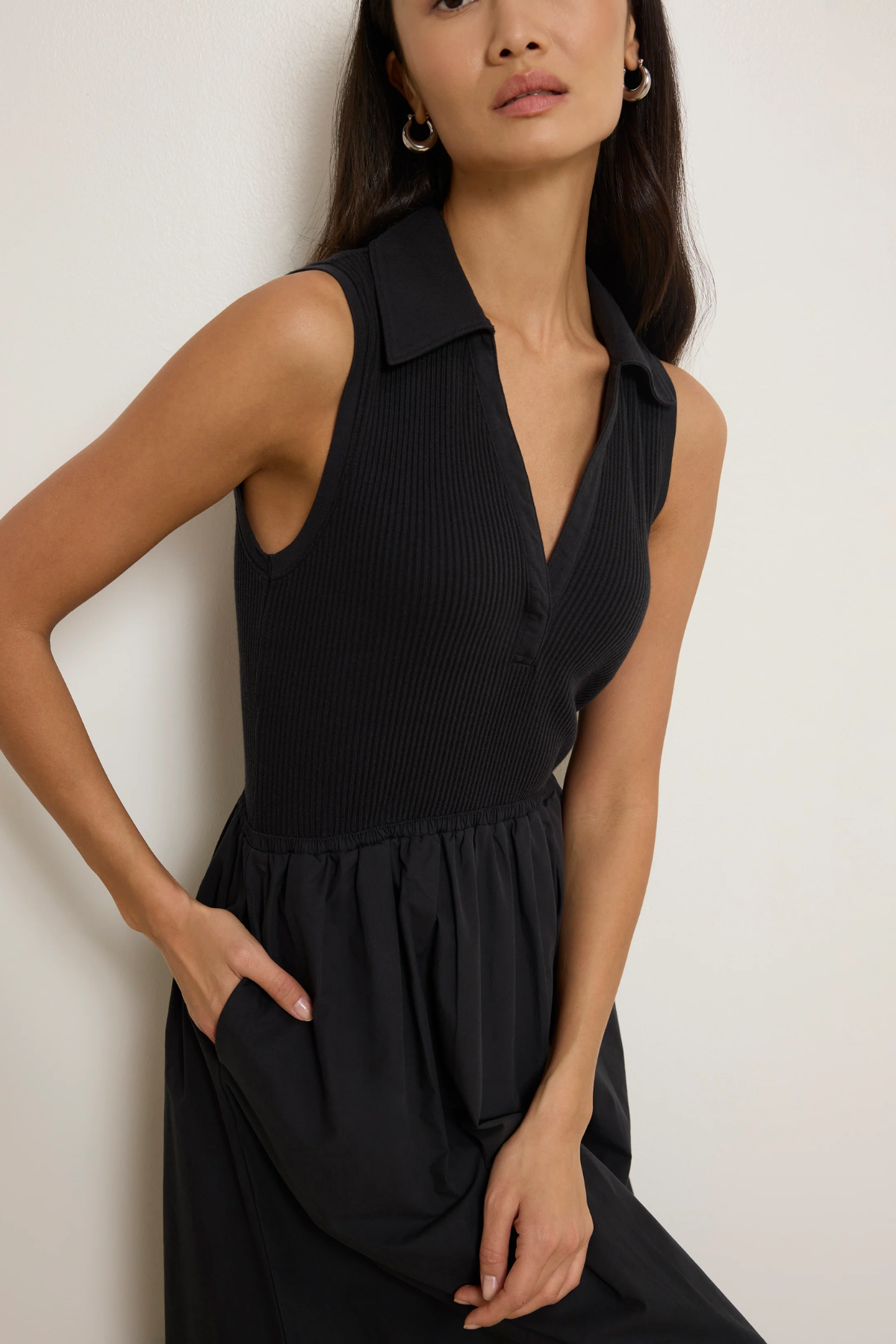 Woman wearing a black sleeveless dress against a white background