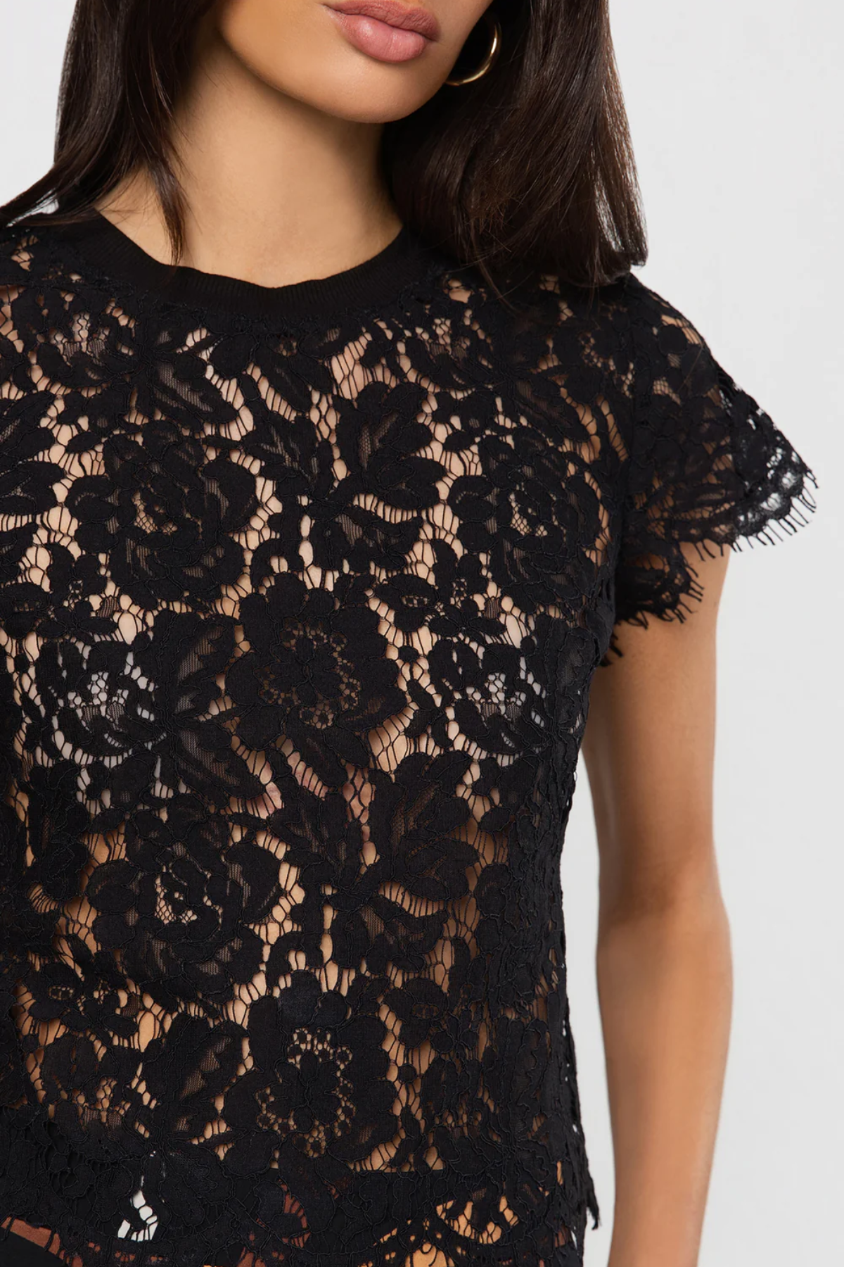 Black lace top on a model against a white background