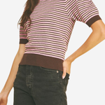 Woman wearing a striped sweater and dark shorts on a plain background