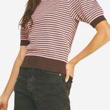 Woman wearing a striped sweater and dark shorts on a plain background