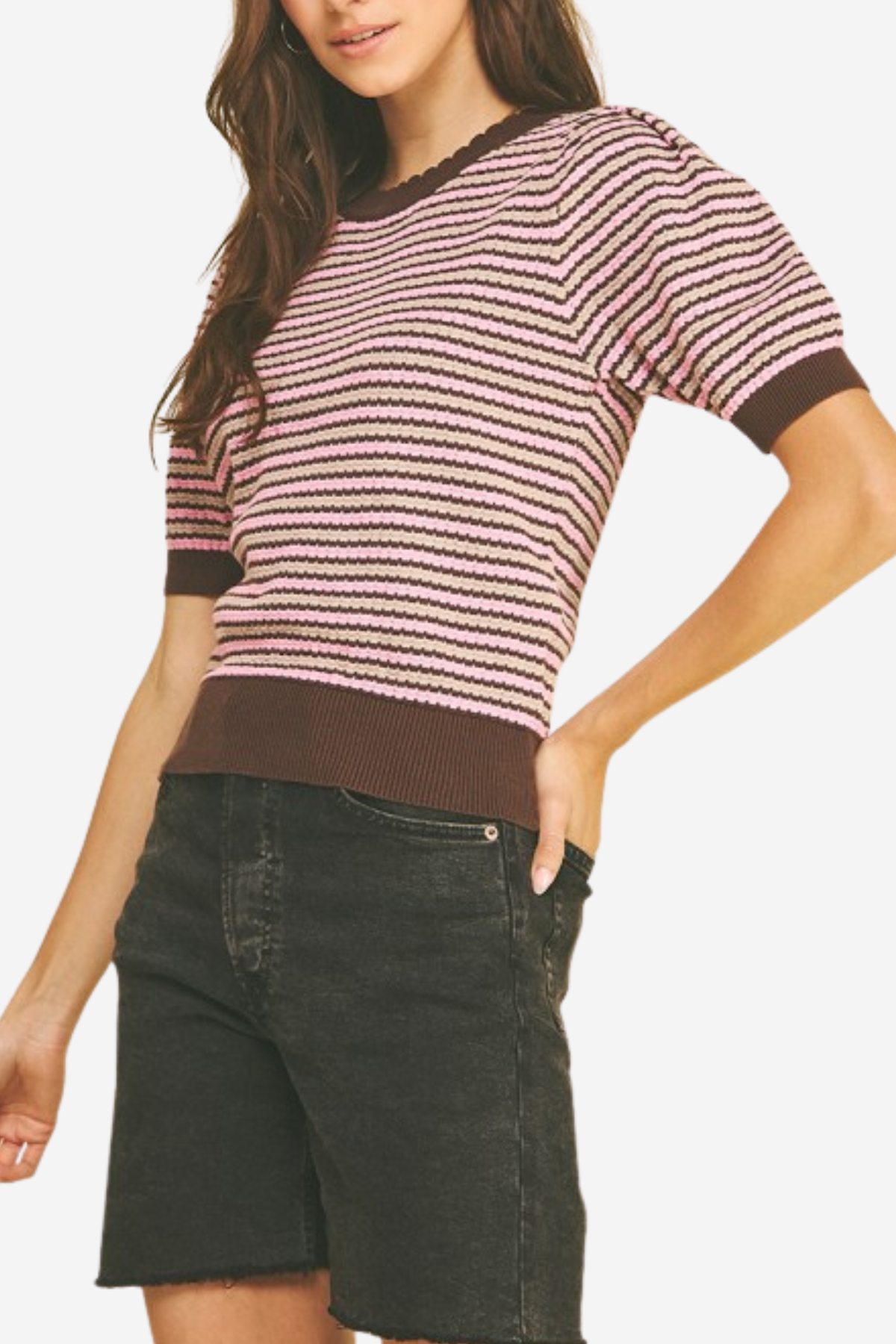 Woman wearing a striped sweater and dark shorts on a plain background