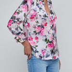 Person wearing a floral blouse and jeans on a gray background