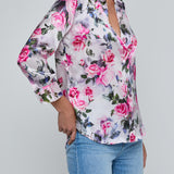 Person wearing a floral blouse and jeans on a gray background